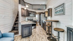 A modern kitchen with dark wood cabinets, a marble countertop, and a built-in oven. - Margarita Time Sfth1 1 Bedroom Home by RedAwning (Port Aransas)