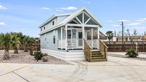 A single-story house with a porch, a staircase, and a fenced yard. - Margarita Time Sfth1 1 Bedroom Home by RedAwning (Port Aransas)