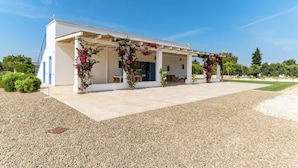 A modern building with a covered patio area, outdoor seating, and a gravel driveway. - Casa Blue con piscina by Wonderful Italy (Ostuni)
