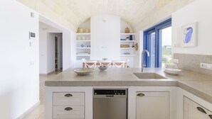 A modern kitchen with a built-in dishwasher, white cabinetry, and a large island with a sink and seating area. - Casa Blue con piscina by Wonderful Italy (Ostuni)