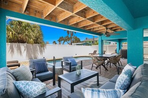 An outdoor patio with a pool, wooden ceiling, and seating area.
