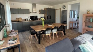 Een moderne keuken met grijze kastjes, een houten eettafel en zwarte stoelen.