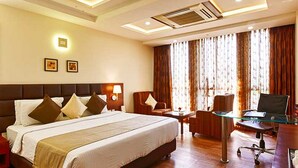 A hotel room with a large bed, a desk, a chair, and a television. - Hotel Page One (Ahmedabad)
