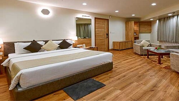 A hotel room with a large bed, a desk, a chair, and a wardrobe. - Hotel Page One (Ahmedabad)