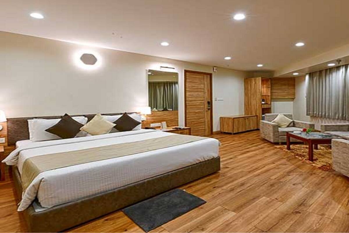 A hotel room with a large bed, a desk, a chair, and a wardrobe.