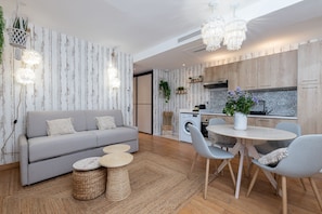 Ein modernes Wohnzimmer mit einem grauen Sofa, einem runden Couchtisch und einem Essbereich mit einem runden Tisch und Stühlen.