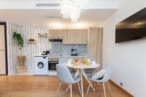 Eine moderne Küche mit Holzausstattung, einer Waschmaschine und einem Essbereich mit rundem Tisch und Stühlen.