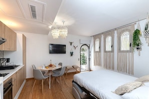 A modern, well-lit room with a dining area, a bed, and a kitchen.
