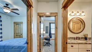 Una camera da letto con un letto, una ventola a soffitto e vista sul corridoio.