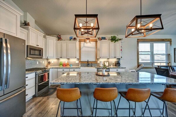 A modern kitchen with white cabinets, a granite countertop, and a central island with bar stools.