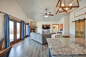 A modern kitchen with a stone countertop, a ceiling fan, and a fireplace.