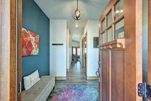 A hallway with a bench, a colorful rug, a wooden door, and a ceiling light fixture.
