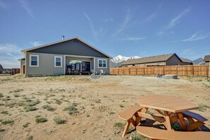 A residential property with a house, a wooden fence, and a picnic table in a dry, grassy yard.