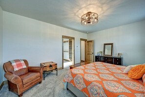 Ein Schlafzimmer mit Bett, Stuhl, Kommode, Spiegel und Deckenleuchte.