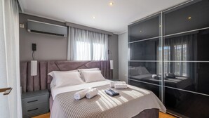 A modern hotel room with a large bed, a wardrobe, and a large window with curtains.