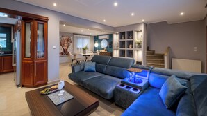 A modern living room with a sectional sofa, a coffee table, and a dining area with a table and chairs.