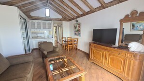 Una sala de estar acogedora con muebles de madera, un televisor y un comedor con sillas y una mesa.