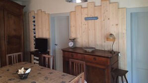 Ein Essbereich mit einem Holztisch, Stühlen, einem Fernseher und einem Schild mit der Aufschrift 'Plage Remember'.