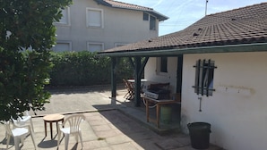 Eine Terrasse mit Sitzgelegenheit im Freien, einem Grill und einer Gasflasche.