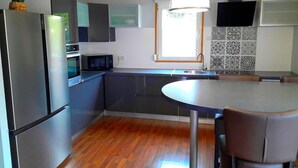 A modern kitchen with a built-in microwave, stainless steel appliances, and a round dining table. - *** NEW CHALET - WIFI - POOL TABLE - TABLE FOOTBALL - GARDEN - CARPORT - 4 BEDROOMS *** (Gérardmer)