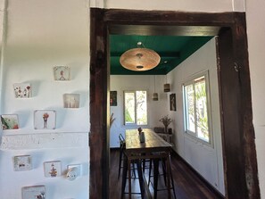 A dining area with a wooden table and chairs, a hanging light fixture, and framed pictures on the walls. - Louisette à la Rivière  (La Rivière St Louis)