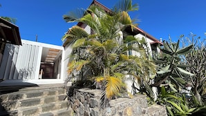 A stone staircase leading to a white building with a red roof, surrounded by tropical plants. - Louisette à la Rivière  (La Rivière St Louis)