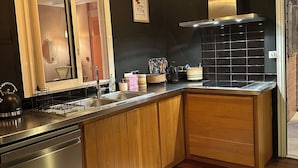 A modern kitchen with wooden cabinets, stainless steel appliances, and pendant lighting. - Louisette à la Rivière  (La Rivière St Louis)