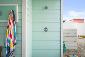 A bathroom with a shower, a towel rack, and a visible hose.