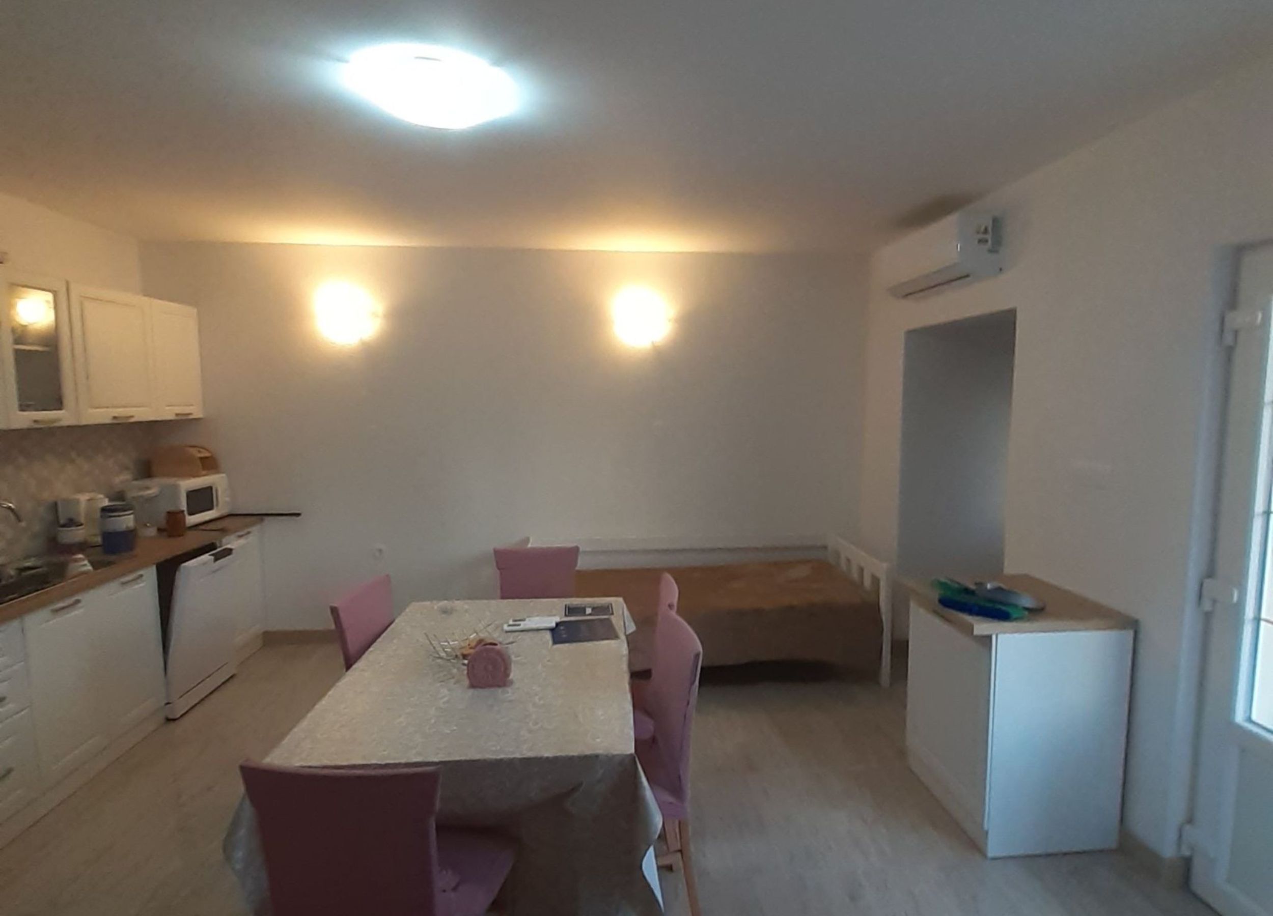 A compact kitchen with a dining area, white cabinets, and a small refrigerator.