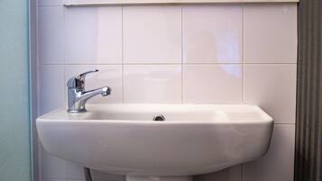 A white bathroom sink with a chrome faucet, set against a tiled wall.