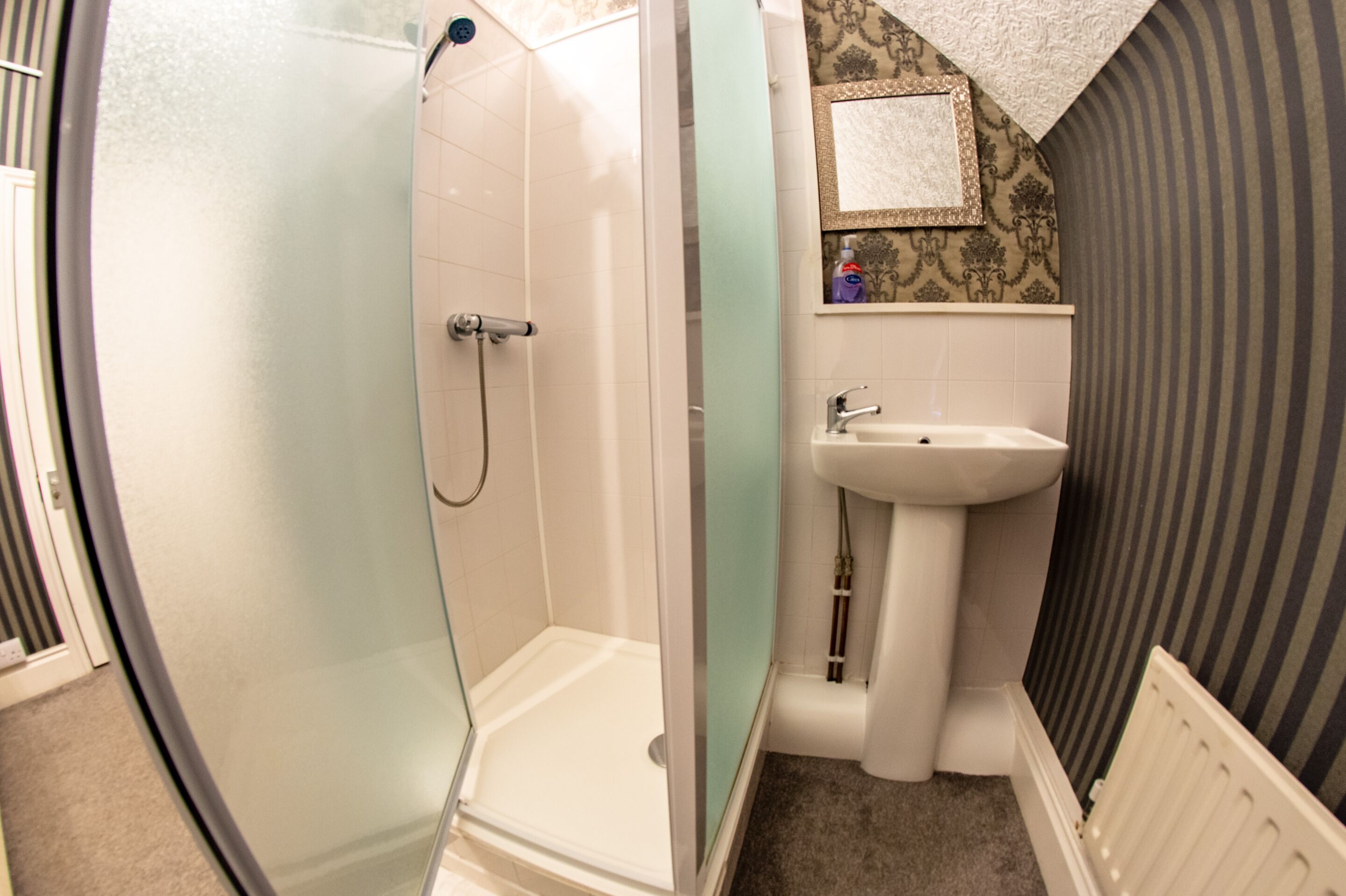 Ein Badezimmer mit Duschkabine aus Glas, Waschbecken und Toilette.