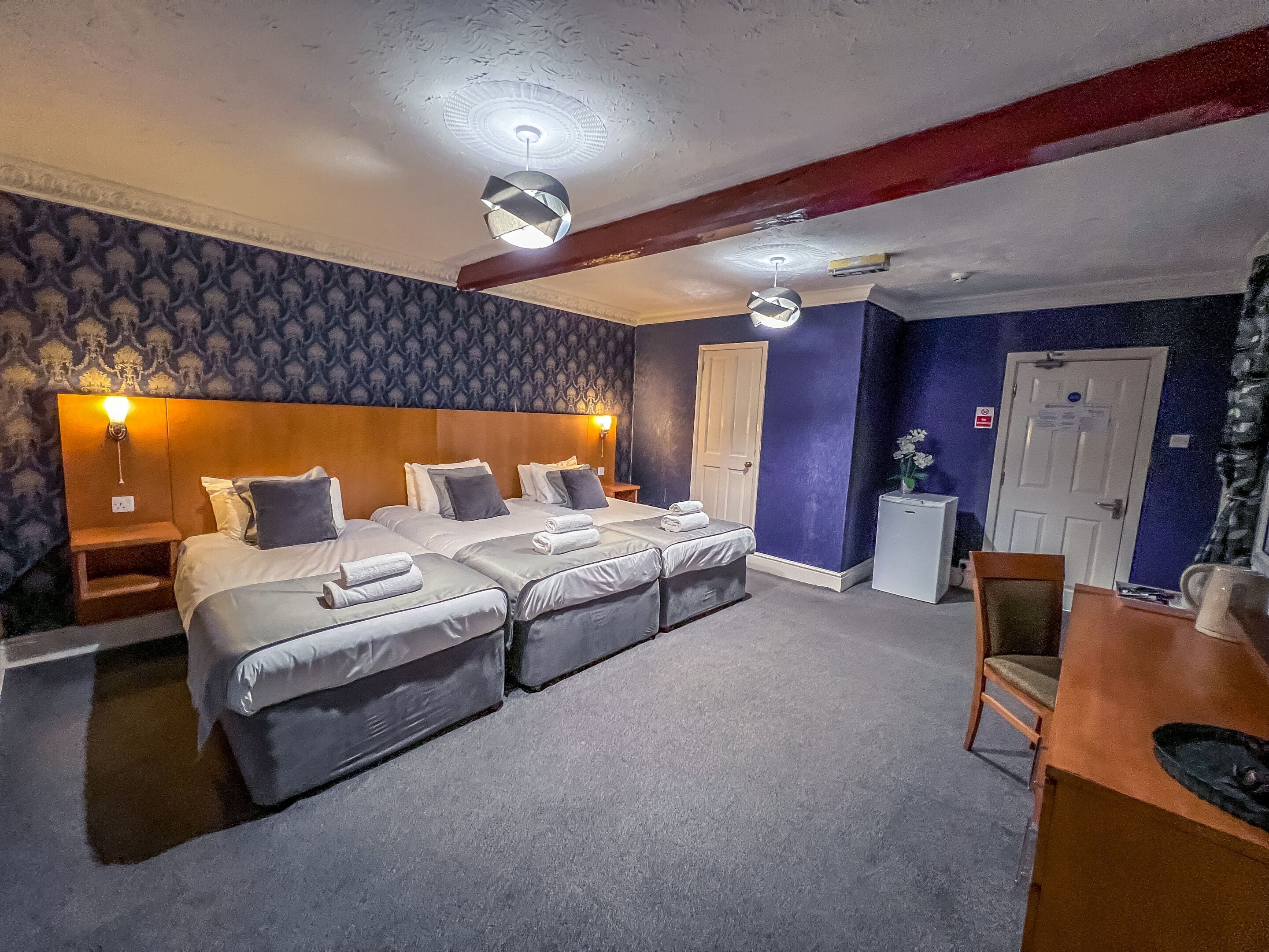 Une chambre d’hôtel avec un grand lit, deux tables de chevet, un bureau et une chaise.