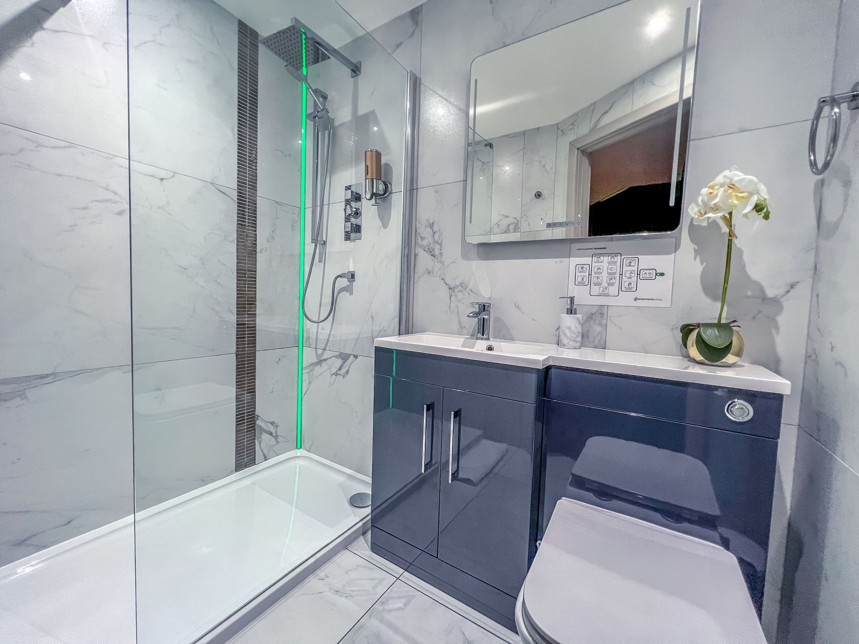 A modern bathroom with a glass-enclosed shower, a vanity with a mirror, and a toilet.