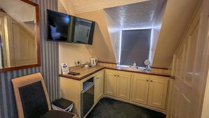 A compact kitchenette with a flat-screen TV, a small sink, and a window. - The Quayside Hotel and Bar (Boston)