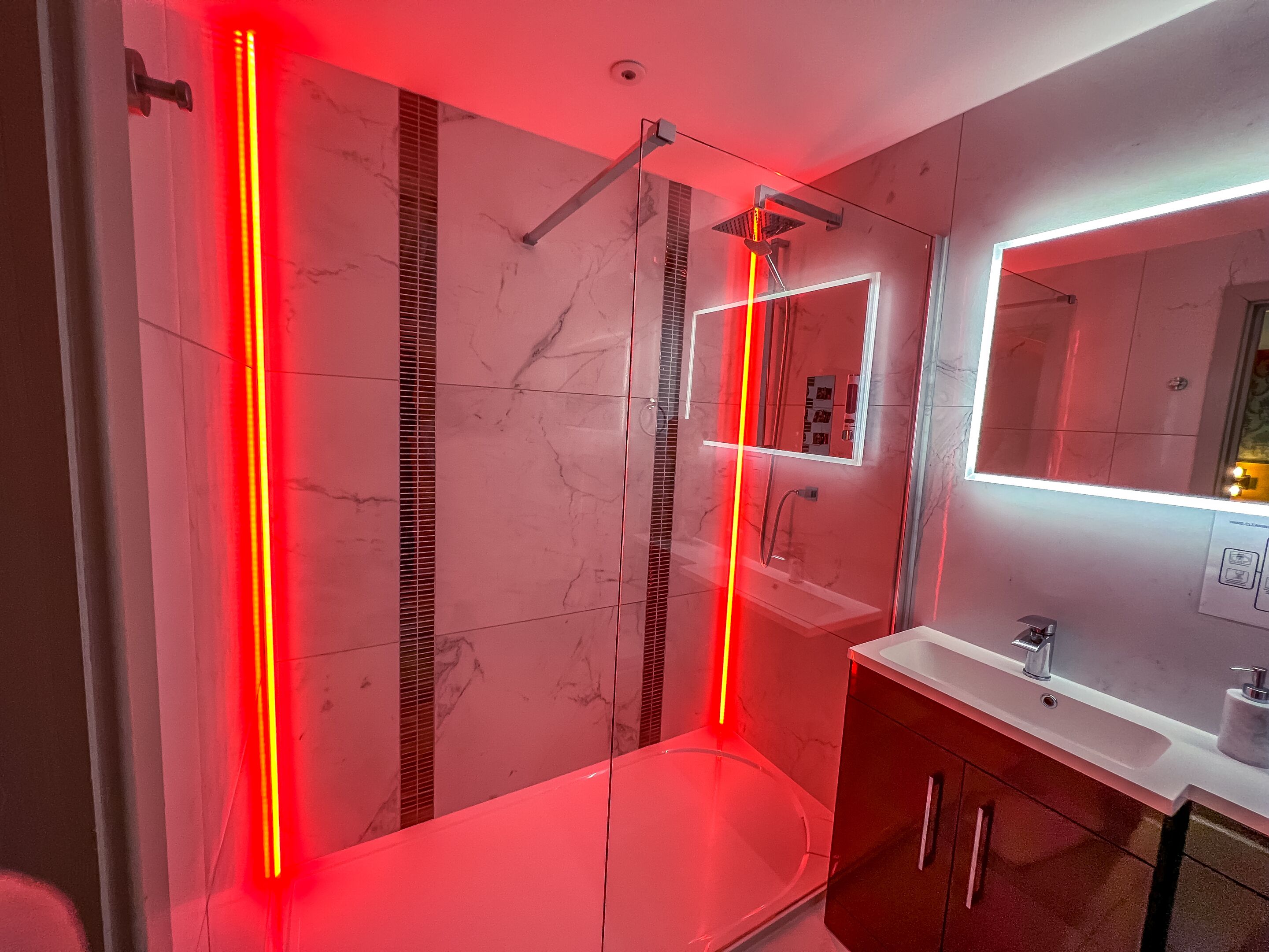 Un baño moderno con cabina de ducha de vidrio, lavabo blanco y espejo.