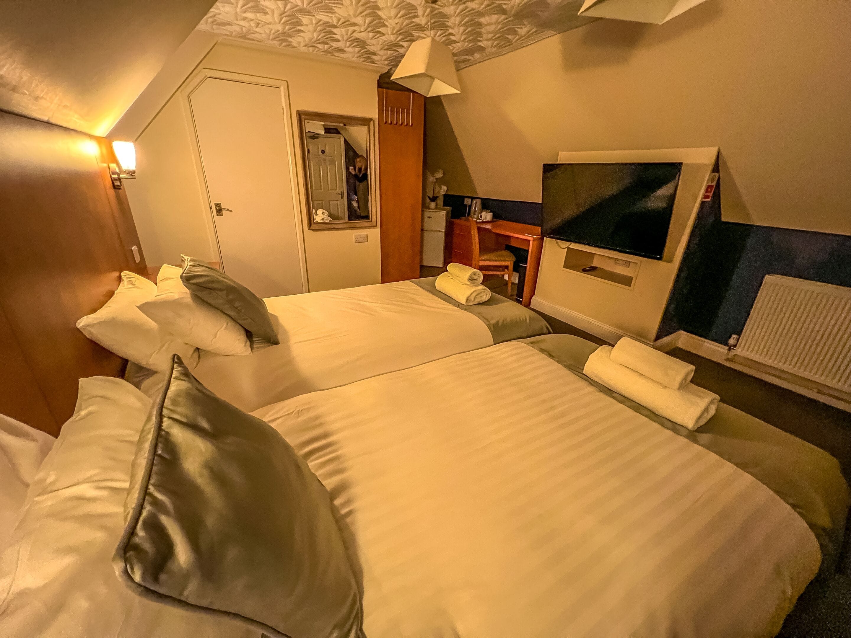 Une chambre d’hôtel avec deux lits, un bureau, une chaise et une fenêtre.