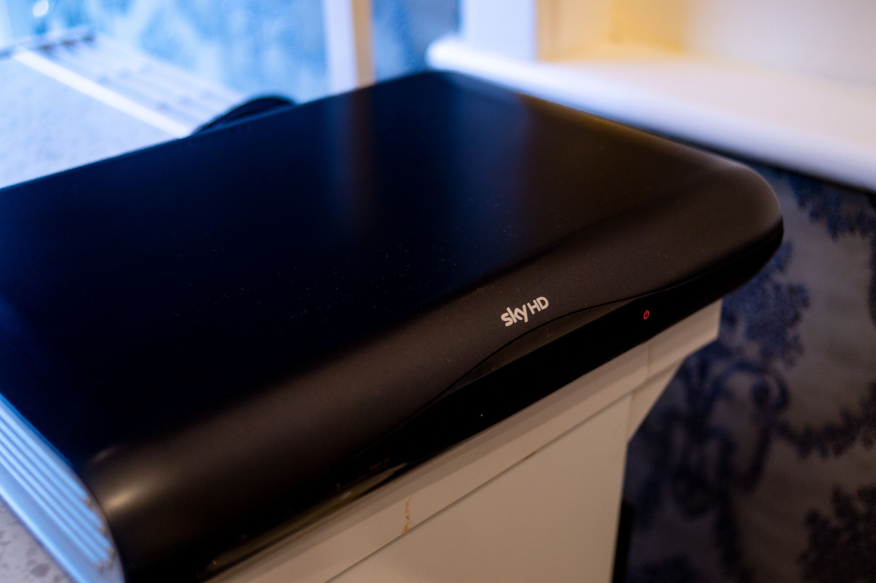 A black SkyHD device on a white surface.