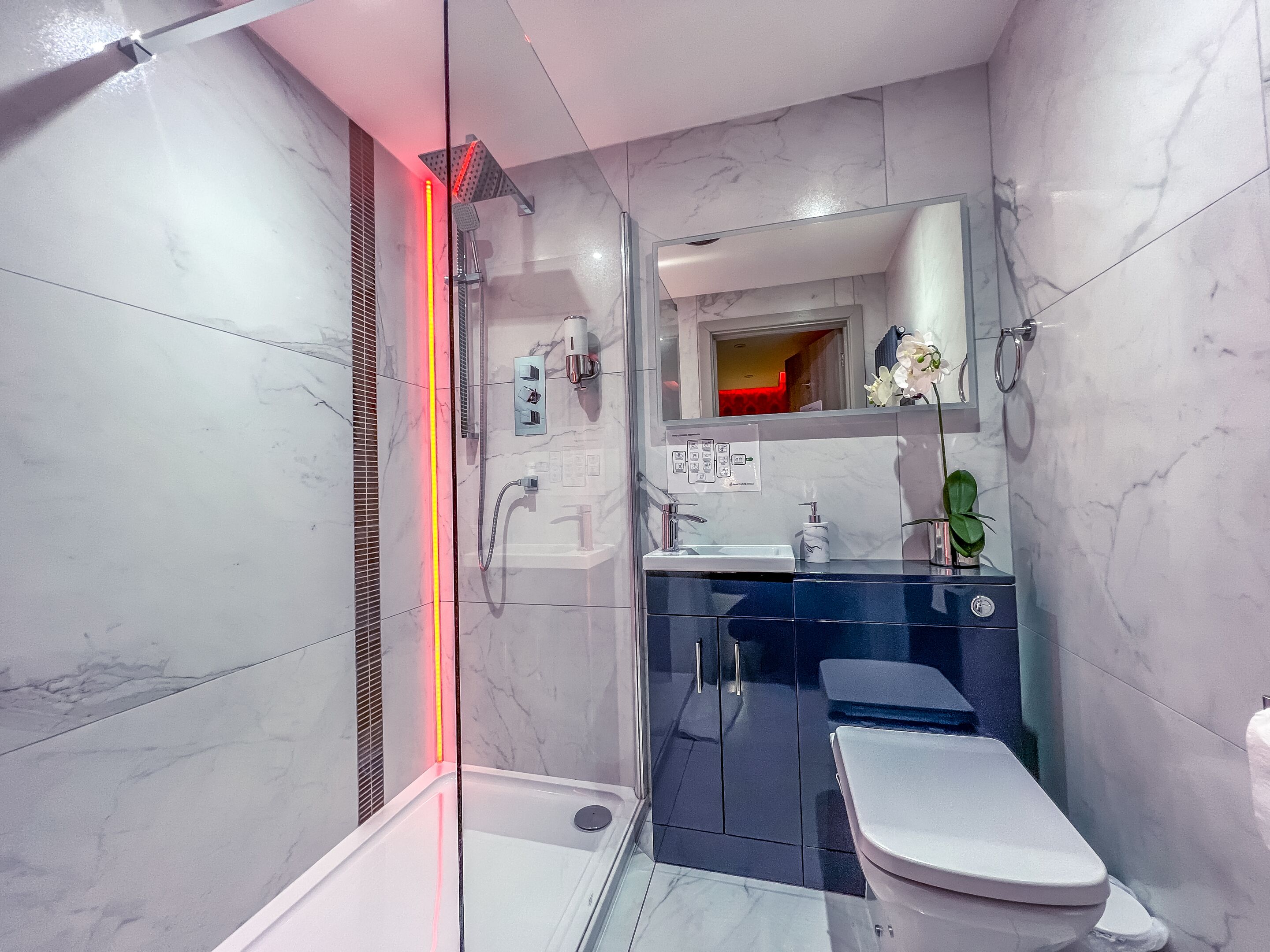 A modern bathroom with a glass-enclosed shower, a vanity with a sink, and a toilet.
