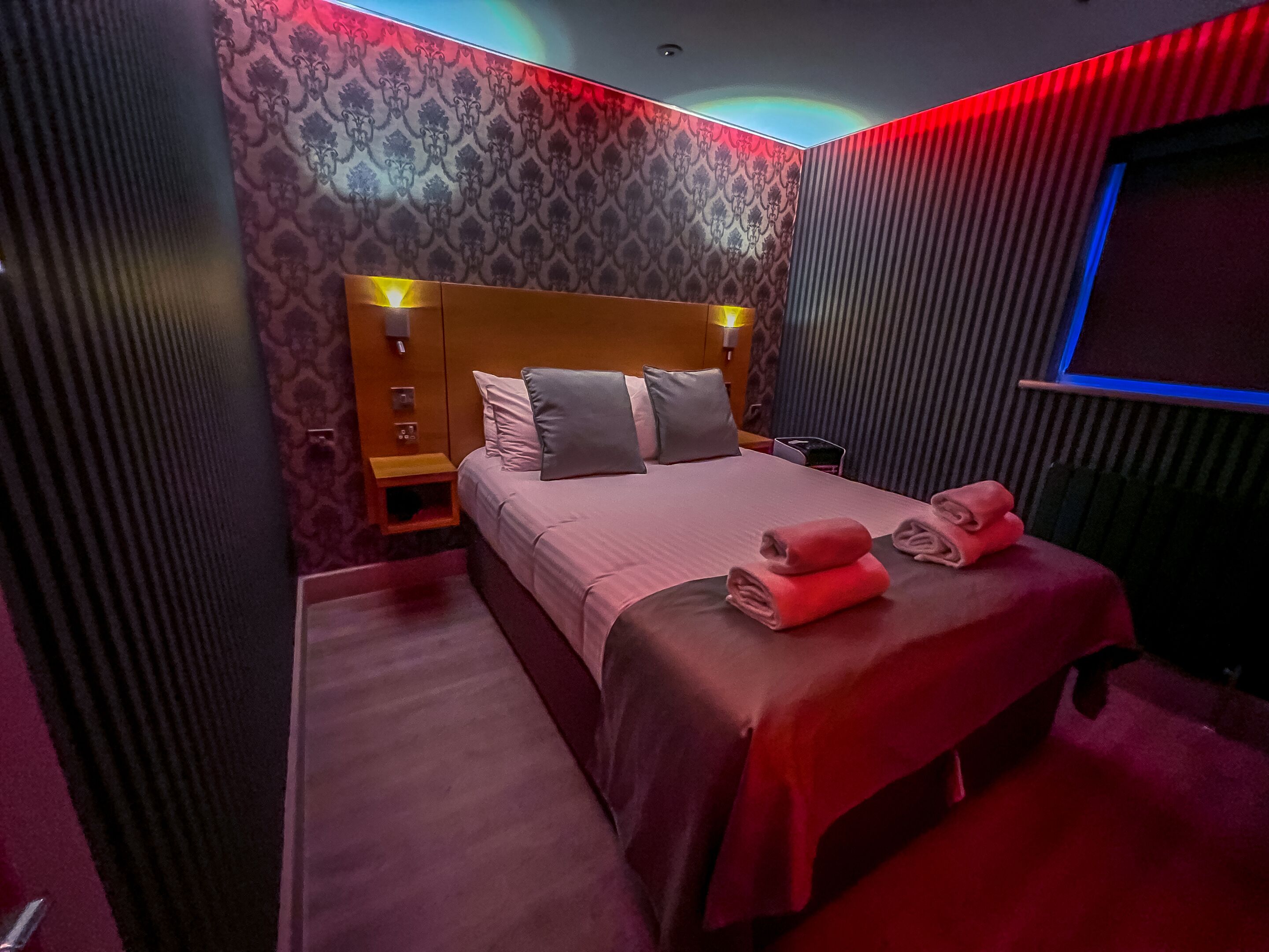 A hotel room with a bed, bedside table, and a TV.
