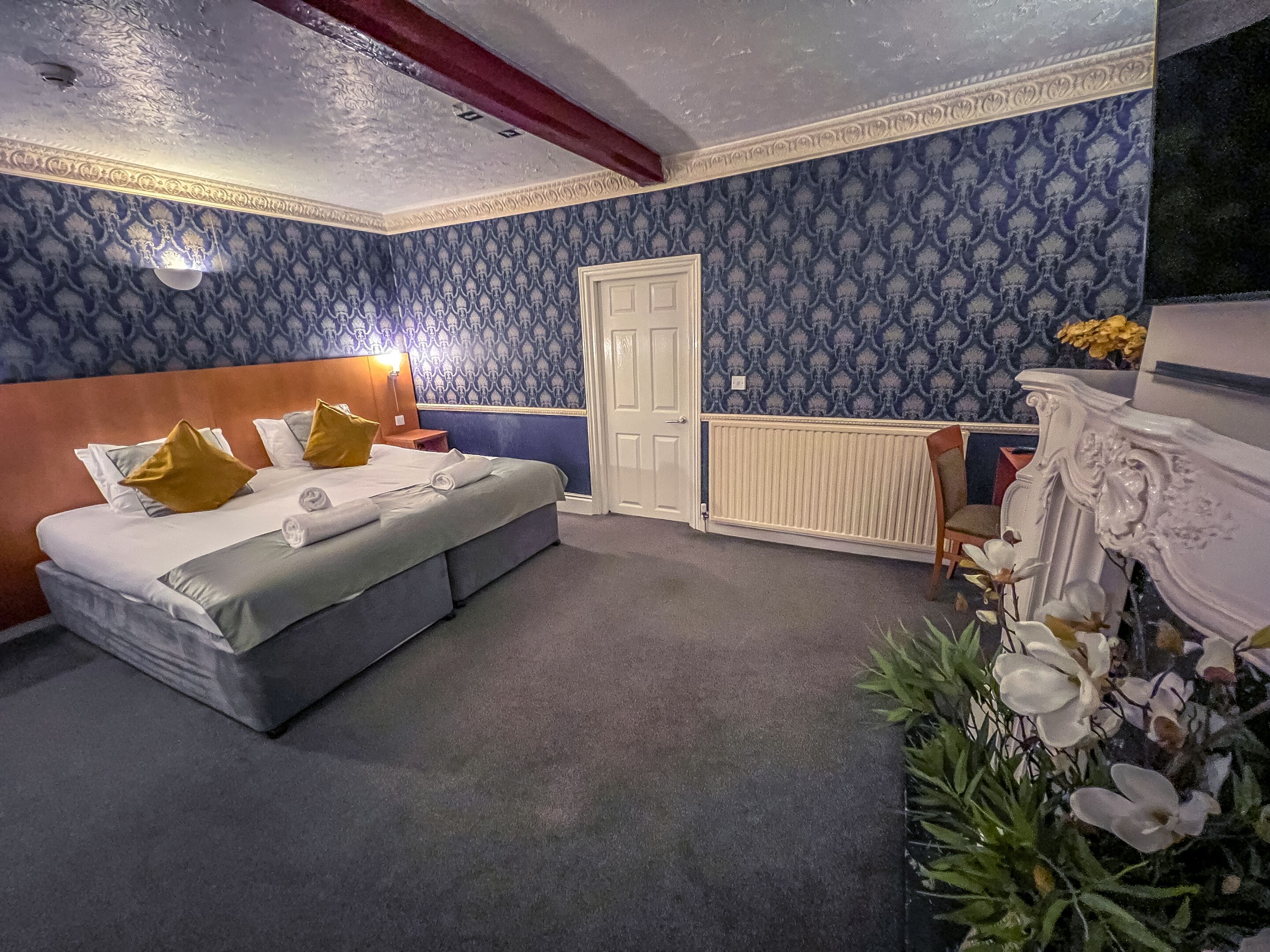 Ein Schlafzimmer mit Bett, Nachttisch, Kommode und Heizkörper.