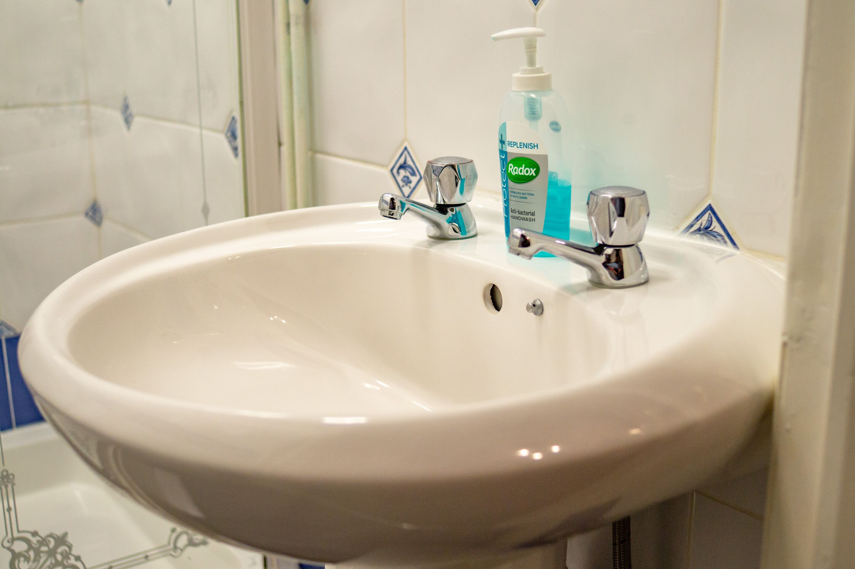 A bathroom sink with a chrome faucet and a bottle of Radox handwash.