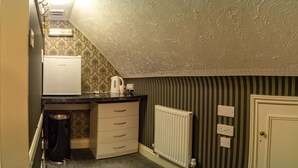 A small kitchenette with a refrigerator, a kettle, and a trash can. There is a radiator and a door to the right. - The Quayside Hotel and Bar (Boston)