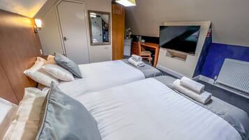A hotel room with two beds, a desk, a chair, a mirror, and a TV.