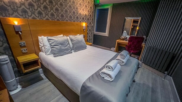A hotel room with a large bed, a nightstand, a desk, and a chair. - The Quayside Hotel and Bar (Boston)