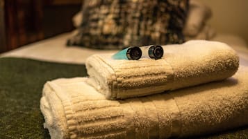 A neatly folded white towel with two black objects on top, placed on a green textured surface.