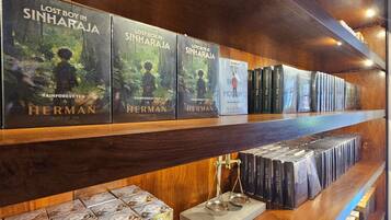 Una estantería con varias copias de 'Lost Boy in Sinharaja' de Rainforest Tea Herman.