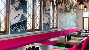 Un restaurant avec un long comptoir, des sets de table colorés et une fresque murale.