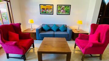 A living room with a blue sofa, two red armchairs, a wooden coffee table, and two lamps on side tables.