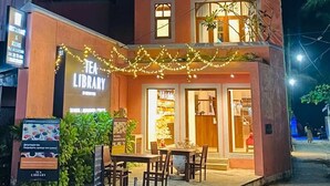 Un bâtiment à deux étages, avec une enseigne indiquant « Bibliothèque de thés » à l’entrée.