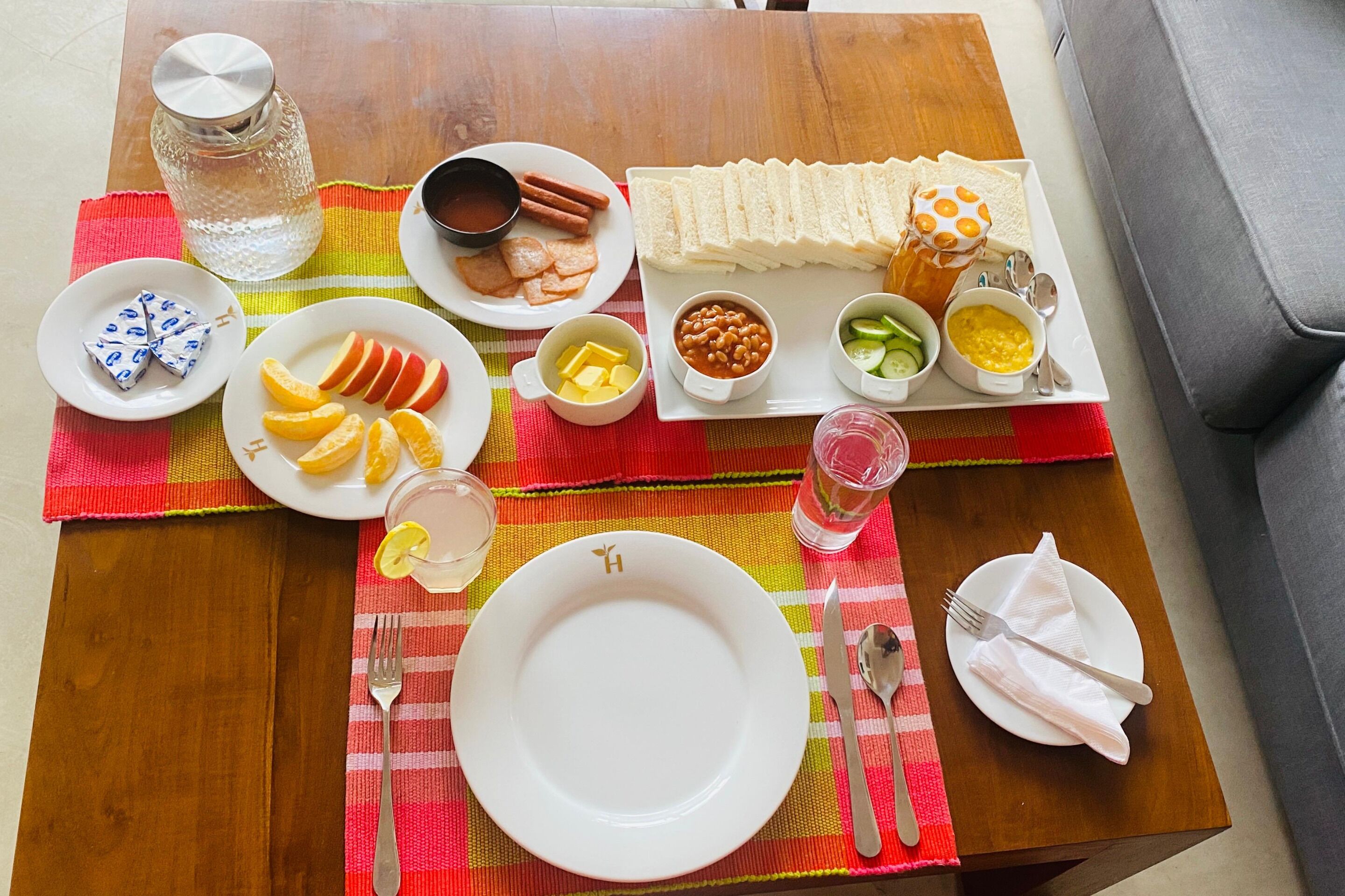 A table set with various food items, including sandwiches, fruits, and condiments.